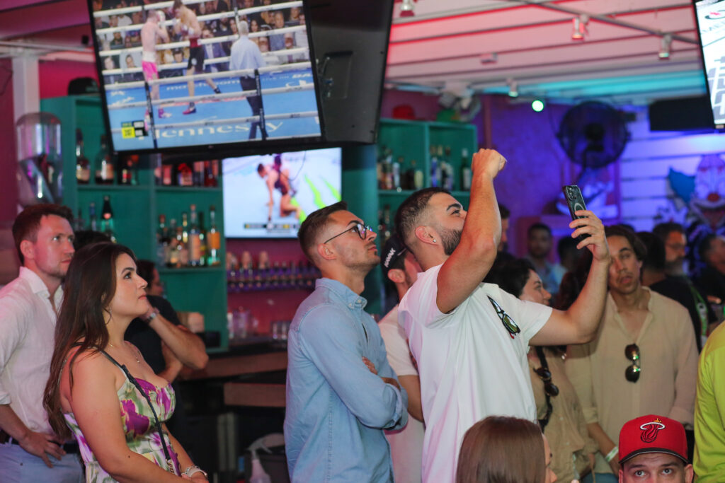 Fans cheering at Grails Sports bar while watching both UFC and boxing on the 70 tvs and full audio