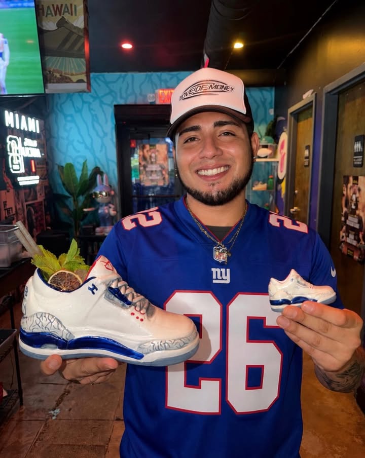 New York Giants fan holding Grails Miami’s sneaker cocktail while wearing a Giants jersey at the Wynwood sports bar.